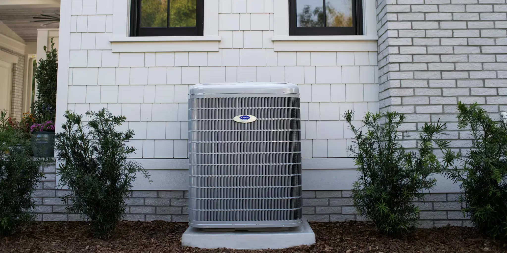 Energy-efficient HVAC system with a 3.5-year payback period chart in Mocksville.A Carrier central air conditioning unit positioned against the exterior wall of a white house between two small shrubs.